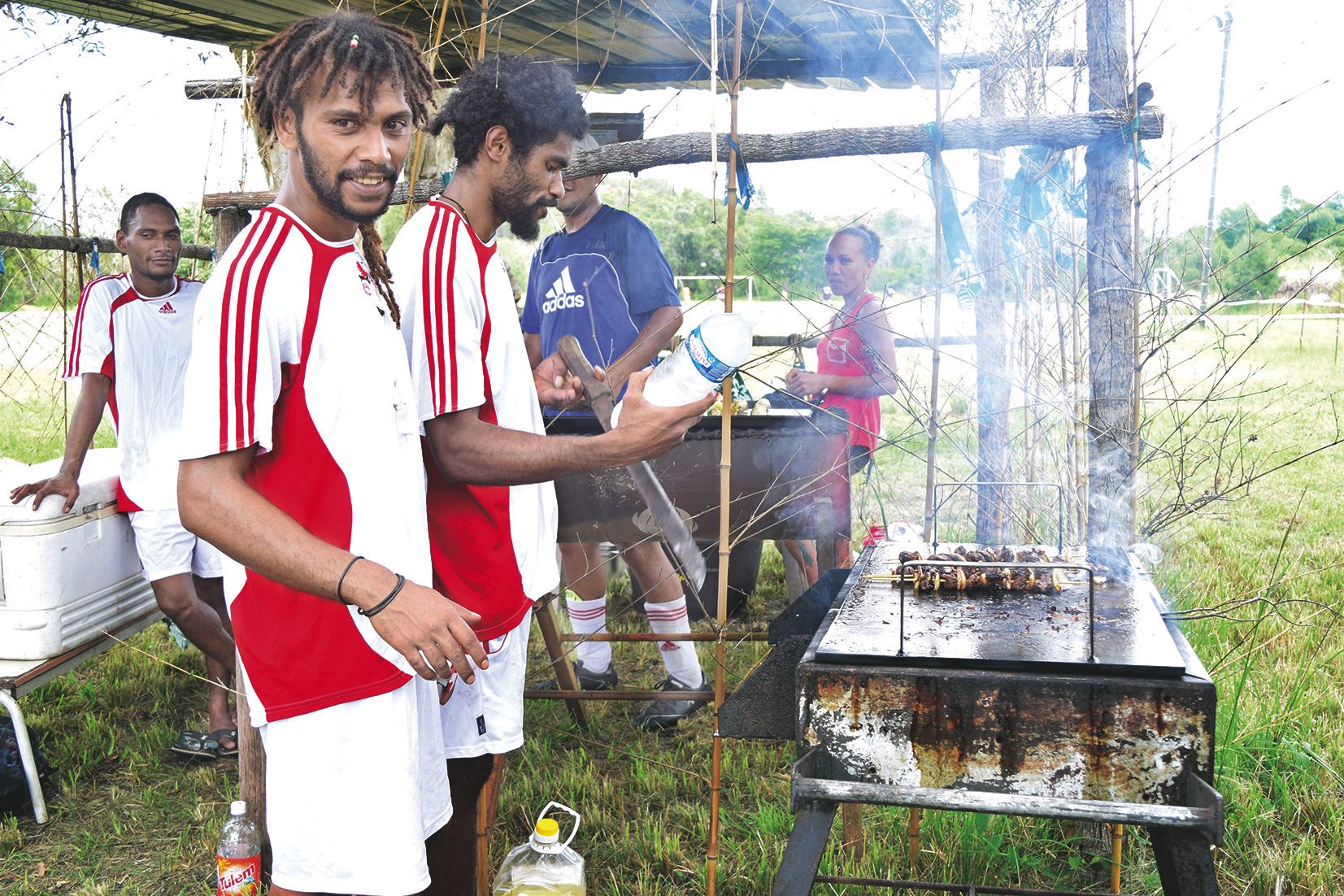 En dehors du terrain, certains joueurs de football sont en charge de la cuisson des brochettes vendues au public.