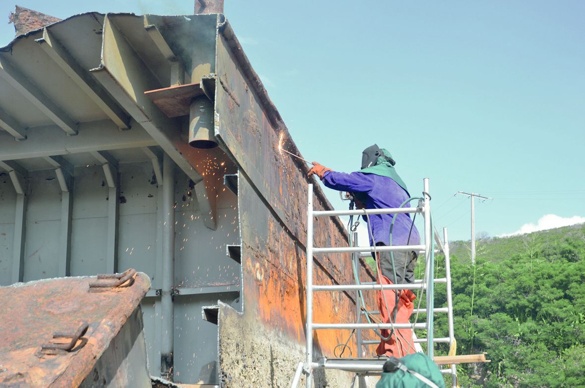 Les deux ouvriers recrutés par Royal recy boat créent des ouvertures à l’extérieur de la barge afin de laisser les fumées s’échapper.