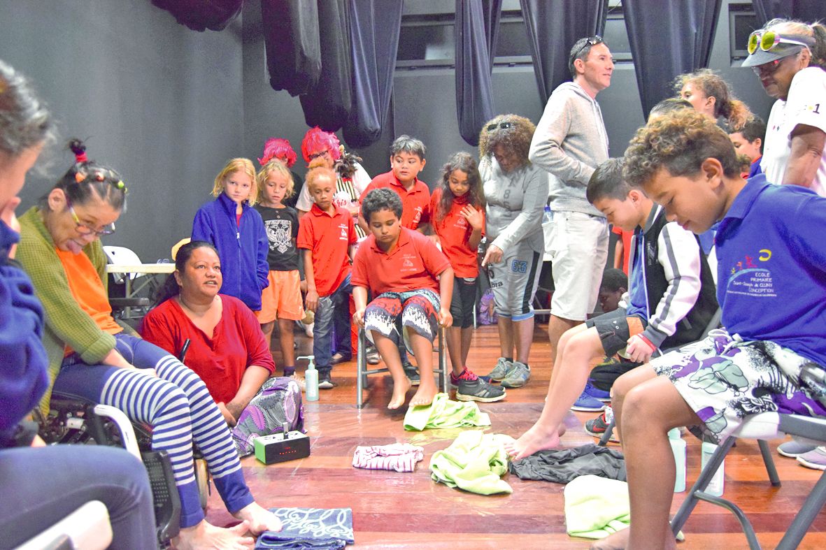 Les jeunes ont aussi découvert les adaptations du quotidien pour les personnes handicapées, comme ici, pendant cette session pliage avec les pieds, dirigée par Bibi (t-shirt orange).