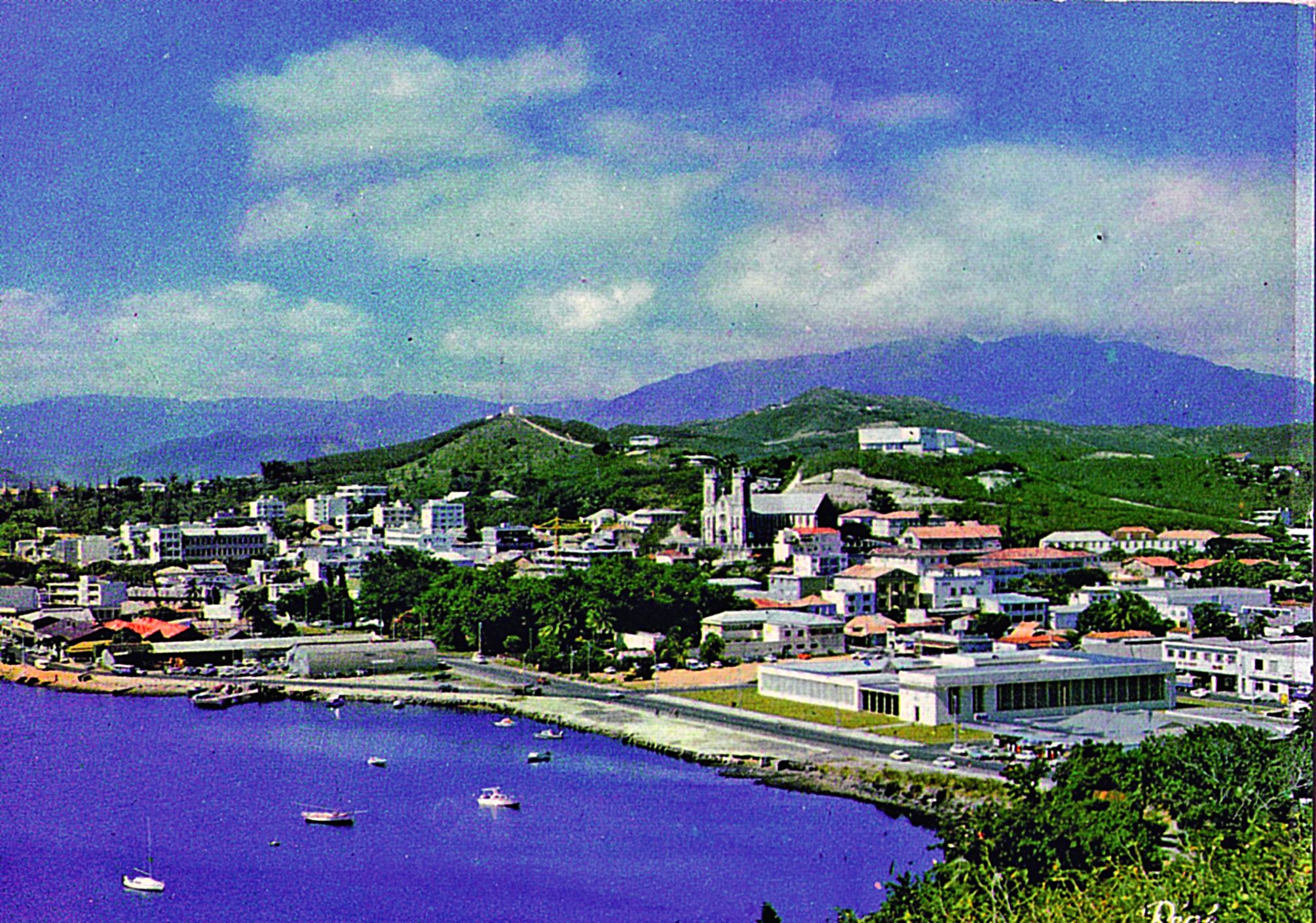 Il s’agit de la même vue. Le ponton a disparu et les remblais ont été valorisés. Le musée, construit en 1970, est bien visible.  À l’époque, il n’est pas entouré de palmiers comme aujourd’hui. En revanche, le bâtiment de l’OPT n’a pas encore été érigé. On