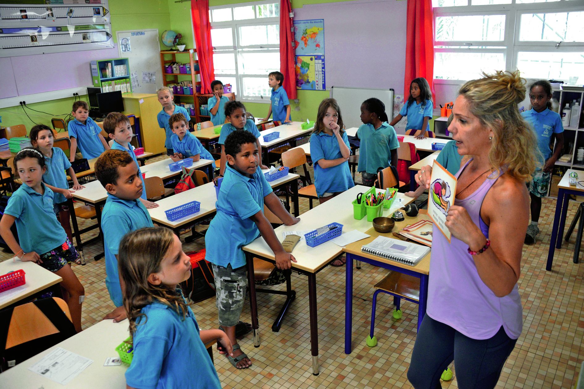 L’intervenante explique les postures aux enfants à l’aide de supports cartonnés, avant de les effectuer avec eux. Photo Thierry Perron