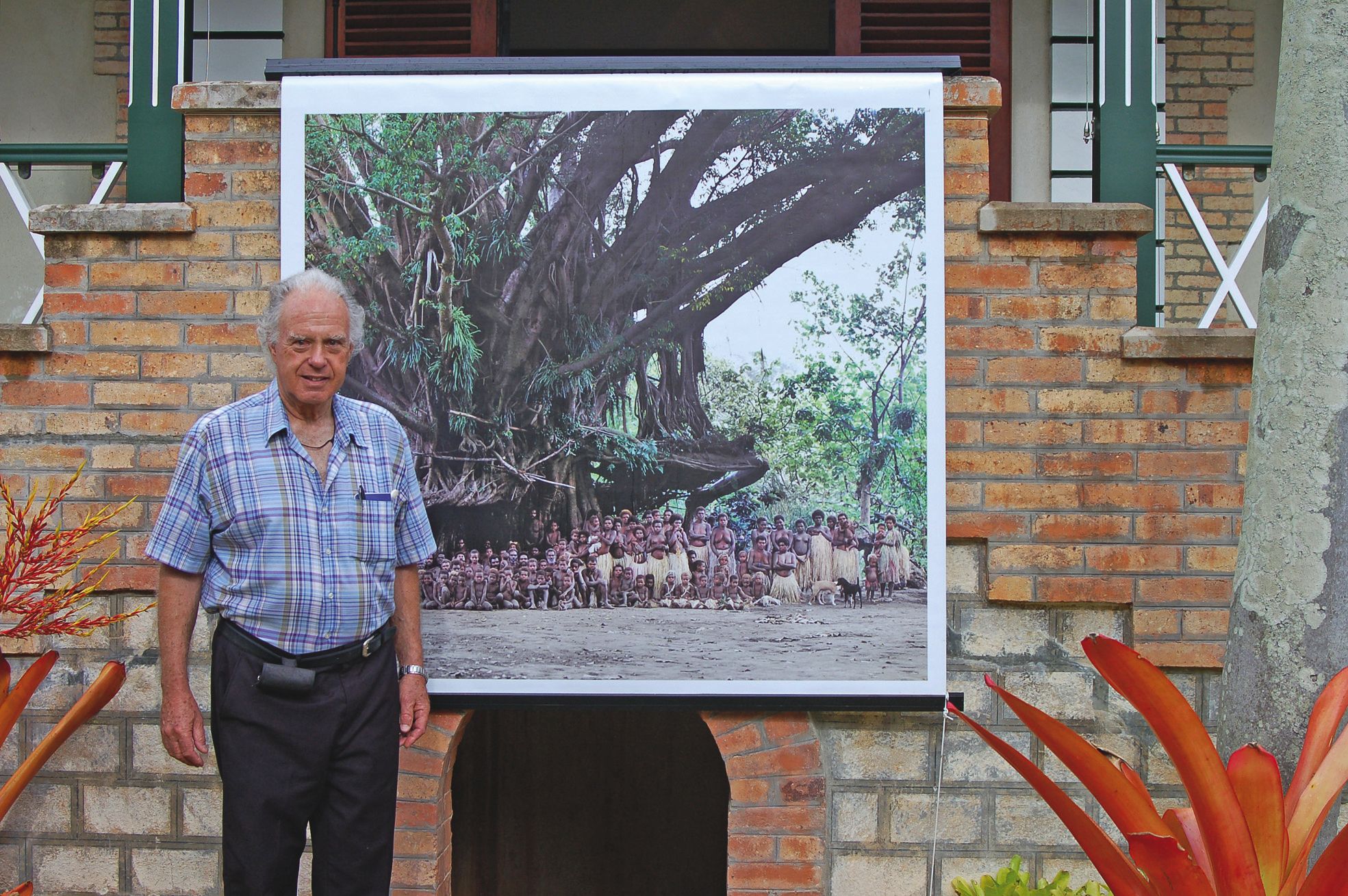 Château Hagen, jeudi 28 avril. David Becker pose devant la photo qui accueille les visiteurs. Celle-ci montre les habitants d'un village du Vanuatu devant le grand arbre sous lequel ils se réunissent.