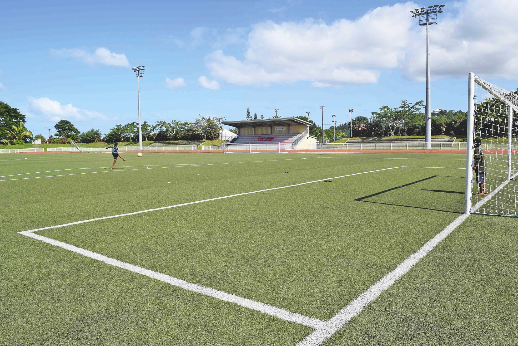 Stade Boéwa, jeudi 9 juin. Georges et Luc, 13 ans, profitent des vacances pour jouer au football. Le terrain synthétique, comme l'ensemble du  complexe de Boulari, est ouvert toute la semaine aux clubs et aux particuliers.