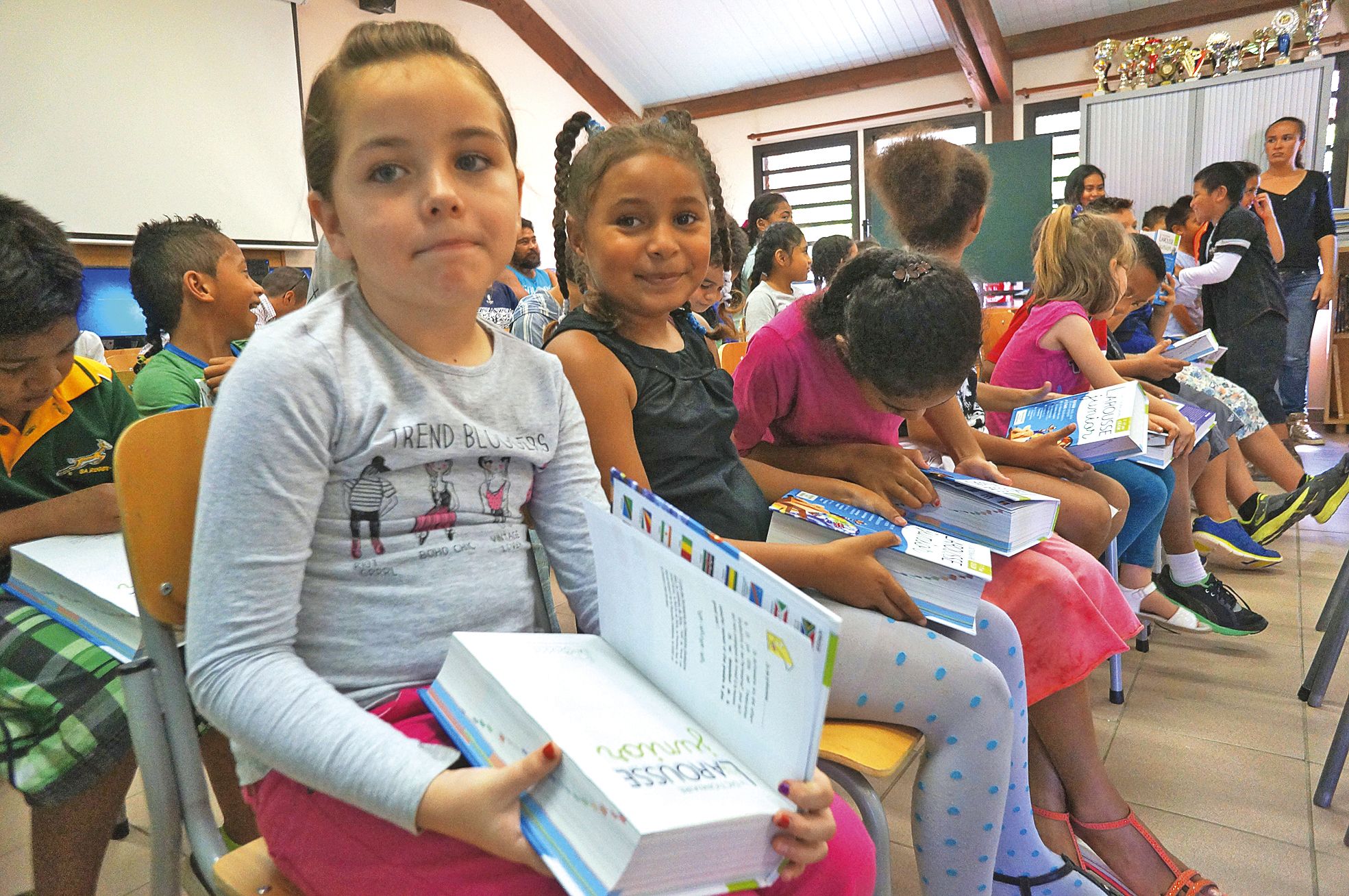 Jeudi 23 juin. Les élèves de CE1 de l'école Les Scheffleras ont reçu des dictionnaires de l'association  Vocabulivre. Ashanti et Emmy sont ravies de ce cadeau qu'elles pourront ramener à la maison.